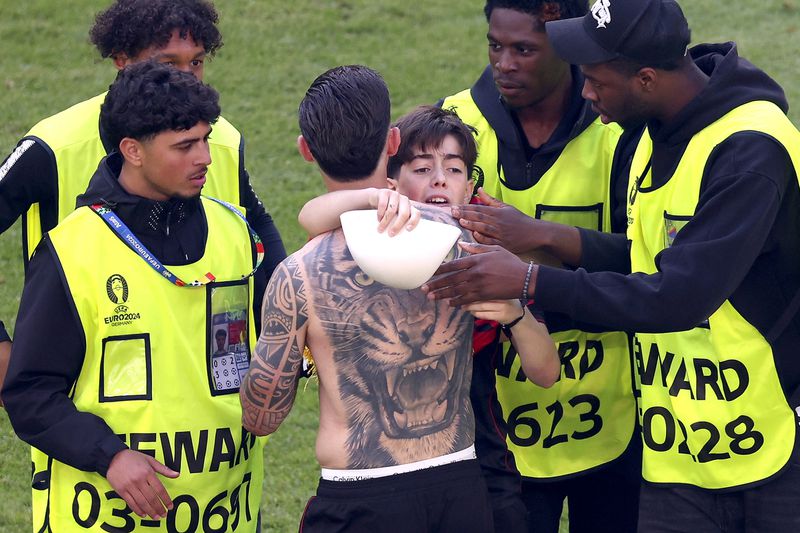 A young streaker, center right, embraces Albania's Elseid Hysaj after a Group B match between Croatia and Albania at the Euro 2024 soccer tournament in Hamburg, Germany, Wednesday, June 19, 2024. (Jens Buettner/dpa via AP)