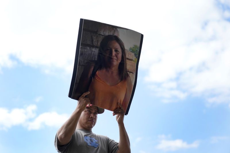 Fernando Ruiz stands silently as he holds a photo of his mother, Lidia Verdugo, who went missing during the flooding caused by Hurricane Helene at Impact Plastics, reminding those attending a press conference she still hadn't been found, in Erwin, Tenn., on Thursday, Oct. 3, 2024. (AP Photo/Jeff Roberson)