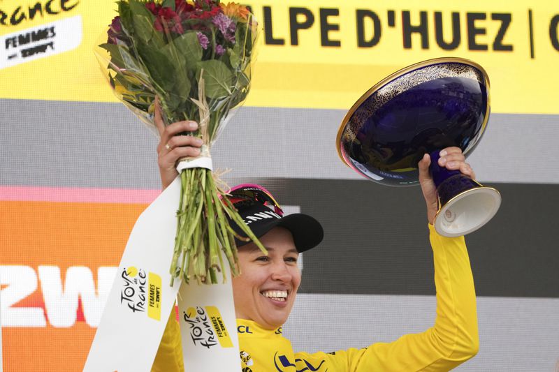 Overall winner Katarzyna Niewiadoma of Poland celebrates on the podium after the eighth stage of the Tour de France Women cycling race with start in Le Grand-Bornand and finish in Alpe d'Huez, France, Sunday, Aug. 18, 2024. (AP Photo/Peter Dejong)