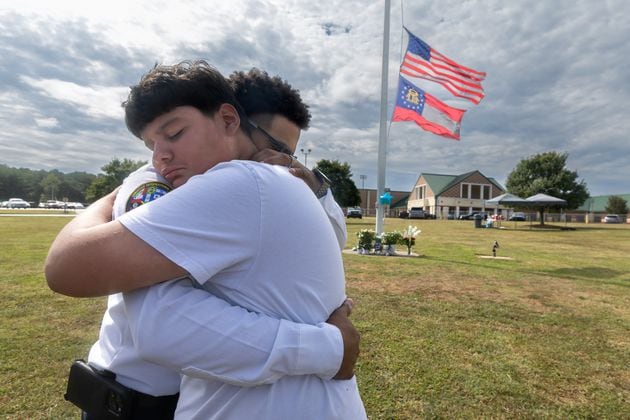 9th grade student, Jose Ortiz-14 (left) is hugged by Georgia State chaplain, Ronald Clark as students and well wishers arrived with flowers to place at the flag pole at Apalachee High School in Winder on Thursday, Sept. 5, 2024. A 14-year-old is accused of shooting and killing two fellow students and two teachers and injuring nine others at Apalachee High School on Wednesday. (John Spink/AJC)