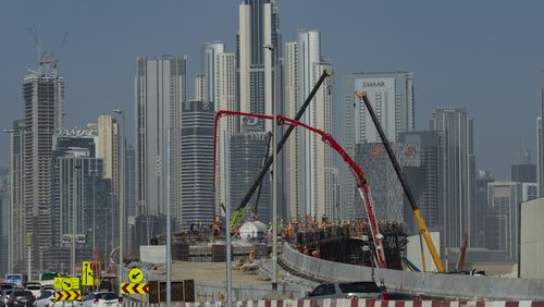 Laborers work at a construction site with skyscrapers towering in the background in Dubai, United Arab Emirates, on Tuesday, Aug. 13, 2024. (AP Photo/Altaf Qadri)