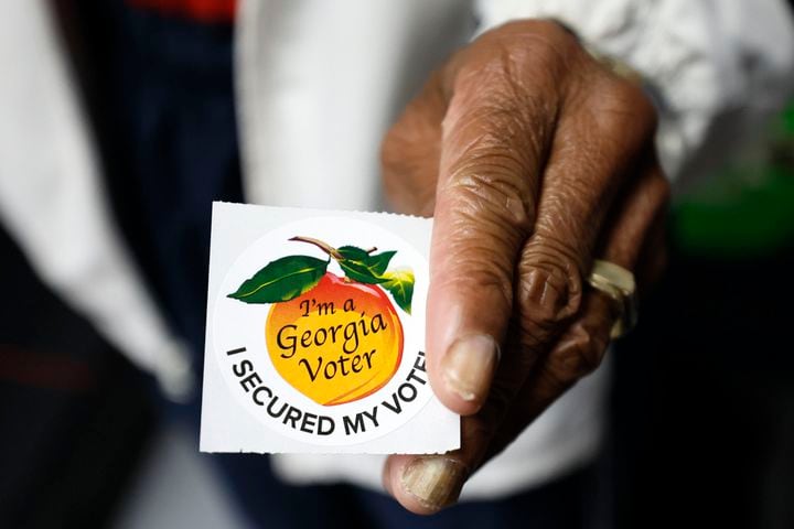 A pool worker holds a Georgia voter sticker ready to be handed to a voter at Berean Christian Church on Monday, October 17, 2022. Miguel Martinez / miguel.martinezjimenez@ajc.com