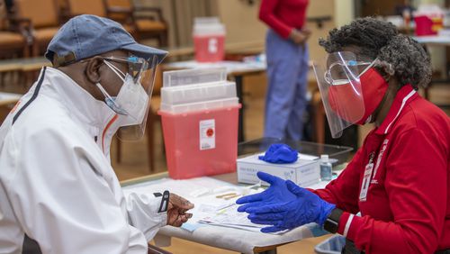 DeKalb County Board of Health medical worker Sandra Armstead, right, explains a few possible symptoms of the COVID-19 vaccination to Rockdale County resident Larry Mitchell after she administered the vaccine to him. (Alyssa Pointer / Alyssa.Pointer@ajc.com)