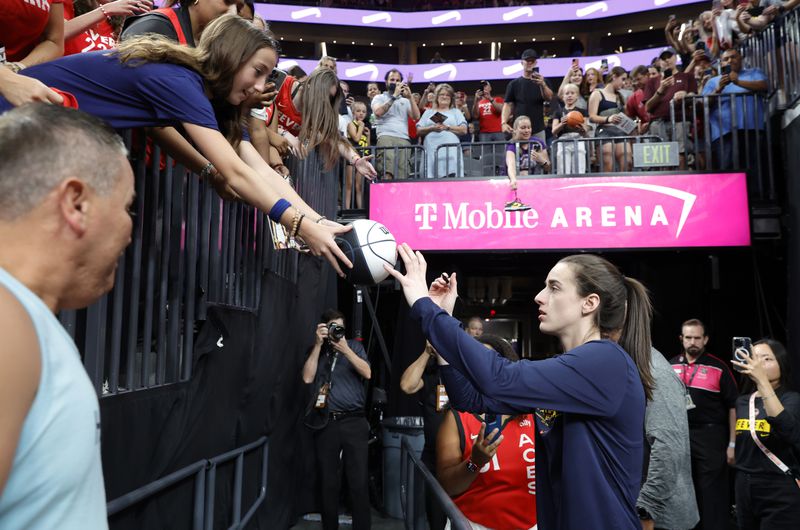 Indiana Fever guard Caitlin Clark autographs a basketball for a fan before a WNBA basketball game between the Las Vegas Aces and the Indiana Fever Tuesday, July 2, 2024, in Las Vegas. (Steve Marcus/Las Vegas Sun via AP)