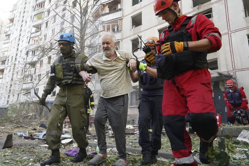 An elderly man is assisted after a Russian aerial bomb struck a multi-story residential building in Kharkiv, Ukraine, Sunday Sept. 15, 2024. (AP Photo/Andrii Marienko)