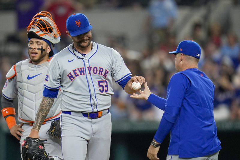 New York Mets pitcher Sean Manaea (59) hands the ball to manager Carlos Mendoza while being switched for a reliever during the sixth inning of a baseball game against the Texas Rangers, Wednesday, June 19, 2024, in Arlington, Texas. (AP Photo/Julio Cortez)