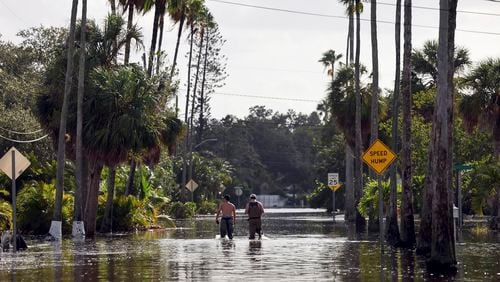 FILE - Men walk down a street flooded by Hurricane Helene in the Shore Acres neighborhood Sept. 27, 2024, in St. Petersburg, Fla. (AP Photo/Mike Carlson, File)