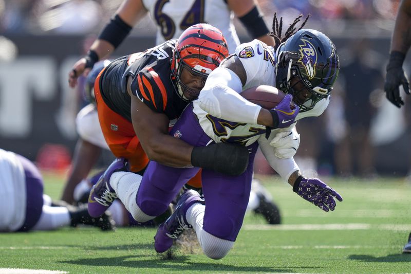 Baltimore Ravens running back Derrick Henry (22) takes a hit from a Cincinnati Bengals defensive tackle Kris Jenkins Jr. during the first half of an NFL football game, Sunday, Oct. 6, 2024, in Cincinnati. (AP Photo/Carolyn Kaster)