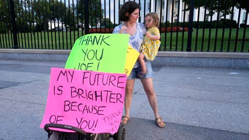 Anna Filipic, of Washington, holds her daughter Louisa Monje, 2, on July 21 outside the White House in Washington, D.C., as they show support for President Joe Biden and his decision to withdraw from his campaign for reelection. (Susan Walsh/AP)