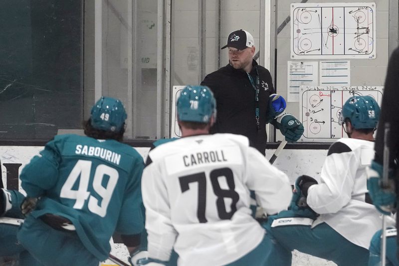 San Jose Sharks head coach Ryan Warsofsky, rear, gives instruction at the NHL hockey team's practice facility in San Jose, Calif., Thursday, Sept. 19, 2024. (AP Photo/Jeff Chiu)