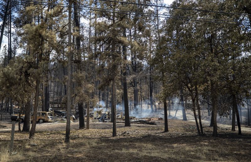 Smoke rises off the remains of a house destroyed by the South Fork Fire in the mountain village of Ruidoso, N.M., Saturday, June 22, 2024. (AP Photo/Andres Leighton)