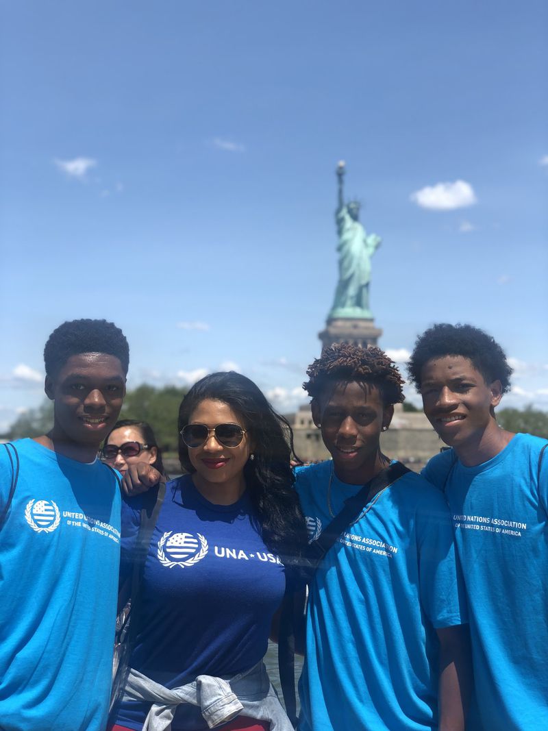 Students Devin Etheridge, Quenyaun Payne and Joshua Fail pose for a photo with U.N. representative Tiffany Irene Coulibaly (second from left) in front of the Statue of Liberty. CONTRIBUTED