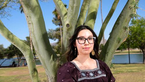 Olivia Yuen, 29, a middle school art teacher and well-known linocut artist in Phoenix, who has a Chinese father and a Mexican mother, stands under a palo verde tree Tuesday, May 21, 2024, in Laveen, Ariz. (AP Photo/Ross D. Franklin)