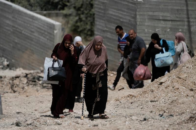 Palestinian families walk along a street as they leave the West Bank Jenin refugee camp during an Israeli military operation, Sunday, Sept. 1, 2024. (AP Photo/Majdi Mohammed)