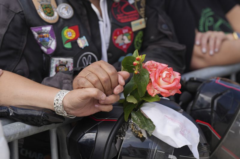 A couple hold hands while attending the IX Pilgrimage of the Blessing of Helmets that draws tens of thousands at the Roman Catholic holy shrine of Fatima, in Fatima, Portugal, Sunday, Sept. 22, 2024. (AP Photo/Ana Brigida)