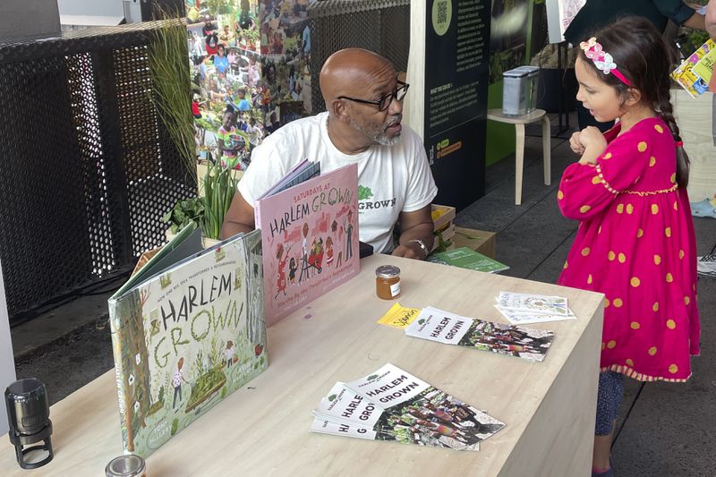 Tony Hillery, founder and CEO of Harlem Grown, a nonprofit that runs urban farms and works with children, speaks with a young fan at the Climate Science Fair on Sunday, Sept. 22, 2024 in New York. (AP Photo/Thalia Beaty)