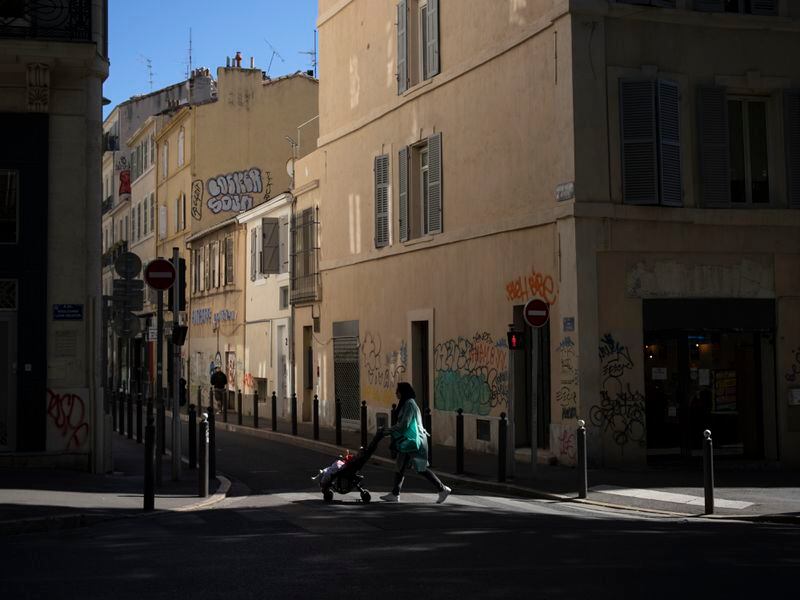 A woman walks through the center of Marseille, southern France, Friday, April 19, 2024. (AP Photo/Daniel Cole)