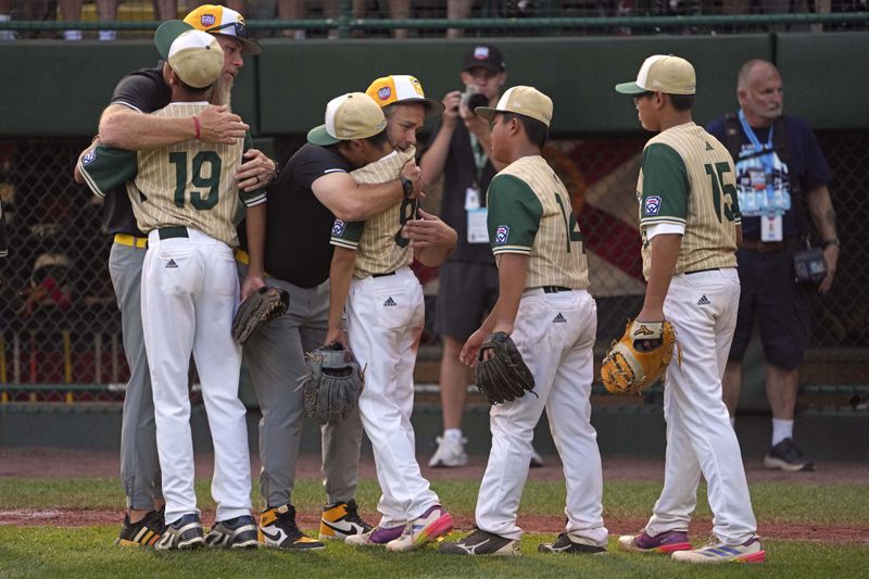 Lake Mary, Fla. coaches Kyle Bone, rear left, and Paul Bibaud, second from left rear, hug players from the Taiwan team after the Little League World Series Championship game in South Williamsport, Pa., Sunday, Aug. 25, 2024. (AP Photo/Gene J. Puskar)