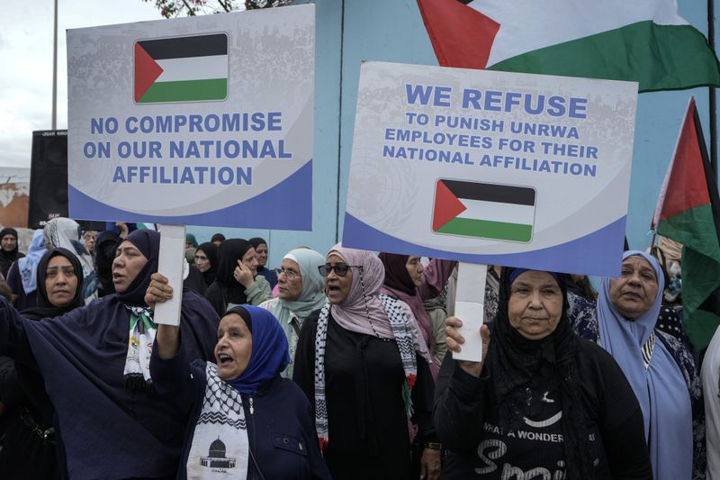 Palestinians in Lebanon hold placards during a protest in front of the United Nations Relief and Works Agency (UNRWA) headquarters in Beirut, Lebanon, Tuesday, Sept. 17, 2024. (AP Photo/Bilal Hussein)