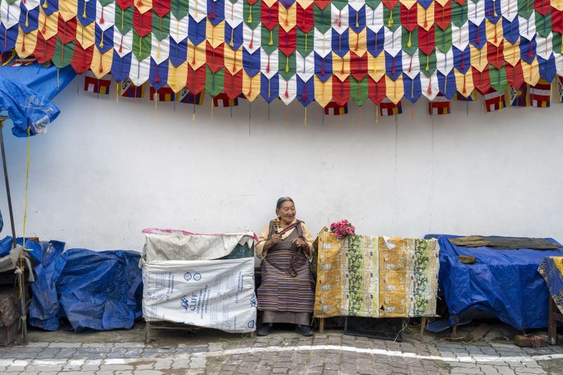 An exiled Tibetan waits with flowers to welcome her spiritual leader the Dalai Lama before he arrives in Dharamshala, India, Wednesday, Aug. 28, 2024. (AP Photo/Ashwini Bhatia)