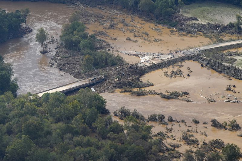 An aerial view a damaged bridge and flooding in the aftermath of Hurricane Helene is seen along the Nolichucky River, Saturday, Sept. 28, 2024, in Greene County, Tenn. (AP Photo/George Walker IV)