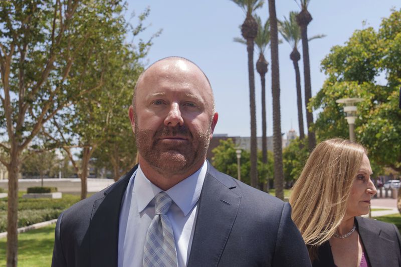 Mathew Bowyer, left, a Southern California bookbinder, arrives with his attorney, Diane Bass, right, in federal court in Santa Ana, Calif., Friday, Aug. 9, 2024. (AP Photo/Damian Dovarganes)