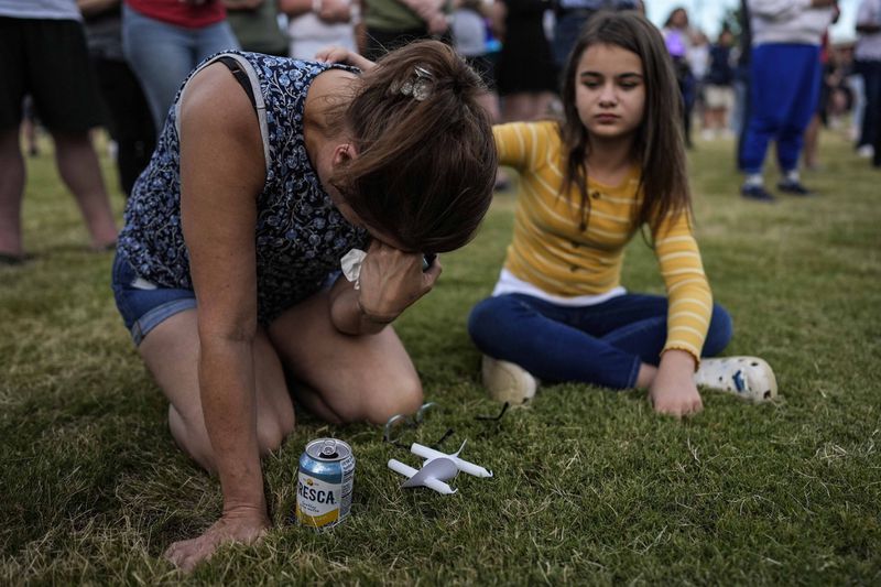 Brandy Rickaba and her daughter Emilie pray during a candlelight vigil for the slain students and teachers at Apalachee High School, Wednesday, Sept. 4, 2024, in Winder, Ga. (AP Photo/Mike Stewart)