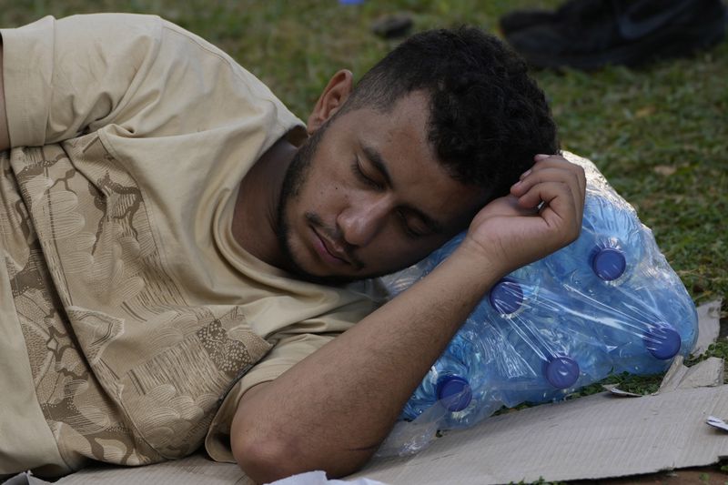 A man who fled the southern suburb of Beirut amid ongoing Israeli airstrikes, sleeps on bottles of water at a park in down town Beirut, Lebanon, Saturday, Sept. 28, 2024. (AP Photo/Hussein Malla)