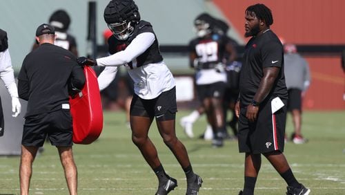 Former Falcons player Courtney Upshaw, right, serving as a coach intern watches as linebacker Arnold Ebiketie (47) participated in a drill during training camp at the Falcons Practice Facility, Friday, July 29, 2022, in Flowery Branch, Ga. (Jason Getz / Jason.Getz@ajc.com)