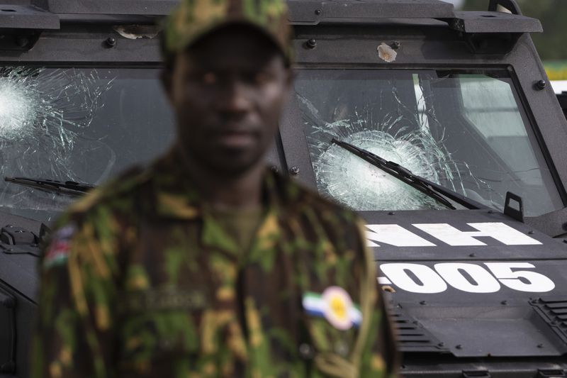 A Kenyan member of the Multinational Security Support (MSS) mission stands next to a Haitian police vehicle donated by the U.S. government and damaged by bullet hits during patrols, in Port-au-Prince, Haiti, Thursday, Sept. 5, 2024. (Roberto Schmidt/Pool photo via AP)