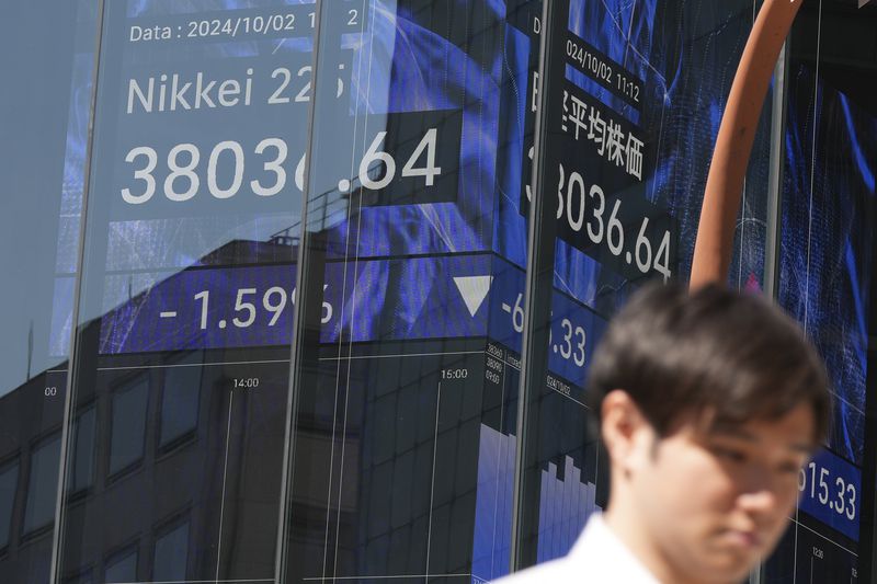 A person walks in front of an electronic stock board showing Japan's Nikkei index at a securities firm Wednesday, Oct. 2, 2024, in Tokyo. (AP Photo/Eugene Hoshiko)