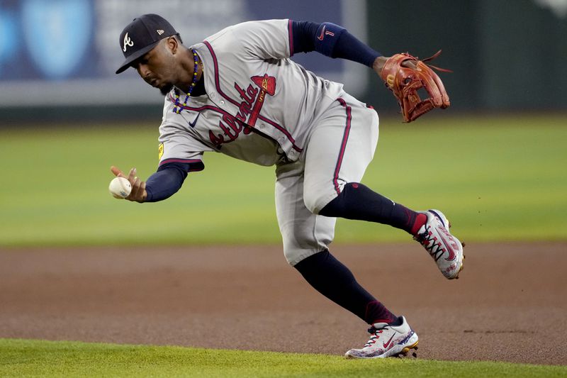 Atlanta Braves' Ozzie Albies bobbles the ball on a base hit by Arizona Diamondbacks' Randal Grichuk during the first inning of a baseball game, Thursday, July 11, 2024, in Phoenix. (AP Photo/Matt York)