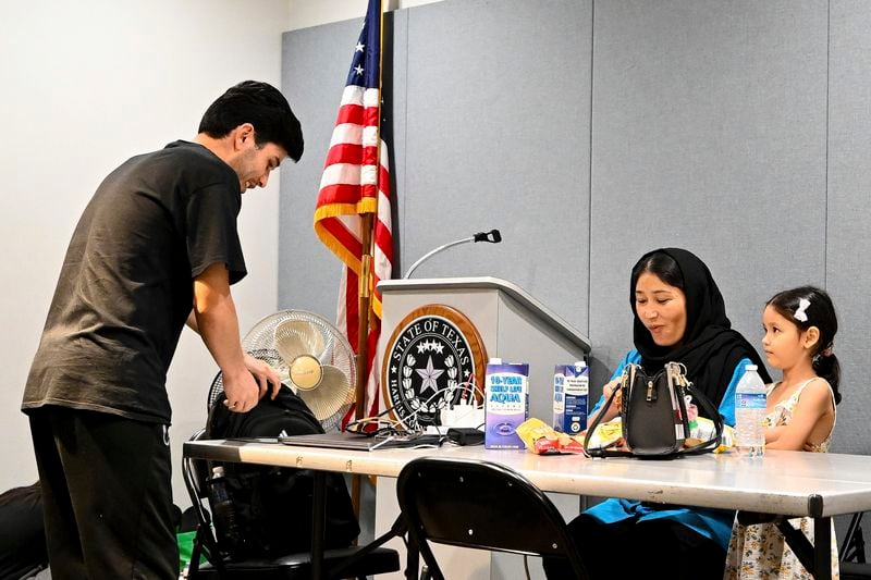 Adila Ebrahimi, center, Yousra Mohammadi, right, and Shukrullah Ibrahimi, left, charge their electronics at a cooling station in Houston, Wednesday, July 10, 2024, after Hurricane Beryl slammed into Texas, knocking out power to millions of homes and businesses. (AP Photo/Maria Lysaker)