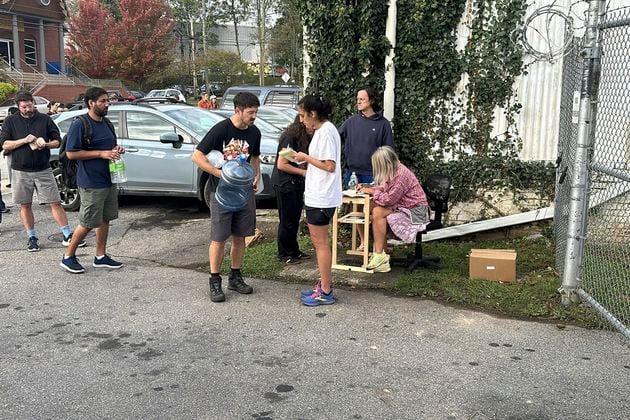 People wait to gather water at Mountain Valley Water in the aftermath of Hurricane Helene in West Asheville, N.C., Monday, Sept. 30, 2024 (AP Photo/Jeffrey Collins)