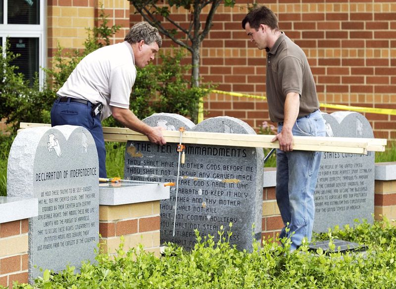 FILE - Workers remove a monument bearing the Ten Commandments outside West Union High School, Monday, June 9, 2003, in West Union, Ohio. Louisiana has become the first state to require that the Ten Commandments be displayed in every public school classroom under a bill signed into law by Republican Gov. Jeff Landry on Wednesday. (AP Photo/Al Behrman, File)