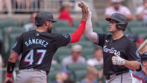 Miami Marlins' Jake Burger, right, high-fives teammate Ali Sánchez, left, as he tags home plate after hitting a three-run home run in the fourth inning of a baseball game against the Atlanta Braves, Sunday, Aug. 4, 2024, in Atlanta. (AP Photo/Jason Allen)