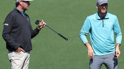 Two-time Masters champion Bubba Watson (left) gives fellow University of Georgia golfer Russell Henley some pointers on pin locations at the second green Monday while they play a practice round for the Masters at Augusta National Golf Club. (Curtis Compton / Curtis.Compton@ajc.com)