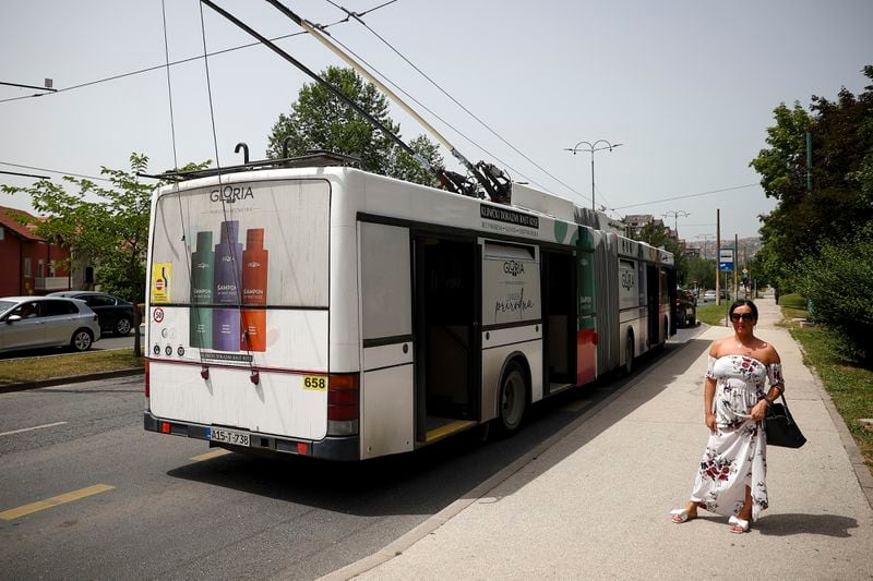 A woman waits next to the trolleybus as the traffic stops due to a power outage in Sarajevo, Bosnia, Friday, June 21, 2024. (AP Photo/Armin Durgut)