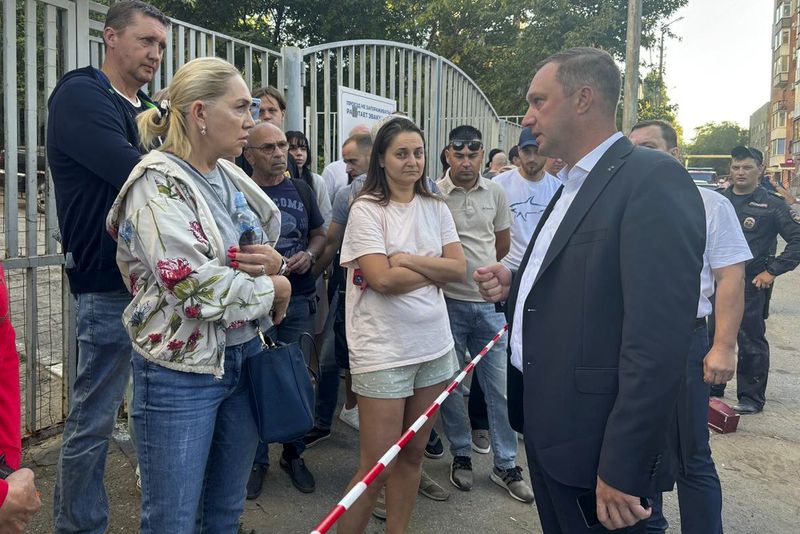 In this photo released by the governor of the Saratov region, Roman Busargin, in his official Telegram channel on Monday, Aug. 26, 2024, governor of the Saratov region Roman Busargin, right, speaks with residents of the building damaged by a drone attack on the city of Saratov, Russia. (Saratov region governor Roman Busargin official Telegram channel via AP)