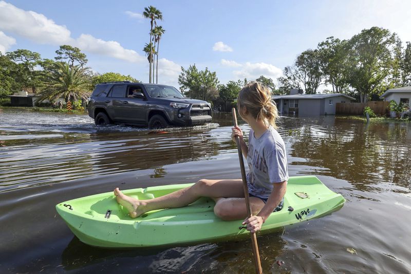 Halle Brooks kayaks down a street flooded by Hurricane Helene in the Shore Acres neighborhood Friday, Sept. 27, 2024, in St. Petersburg, Fla. (AP Photo/Mike Carlson)