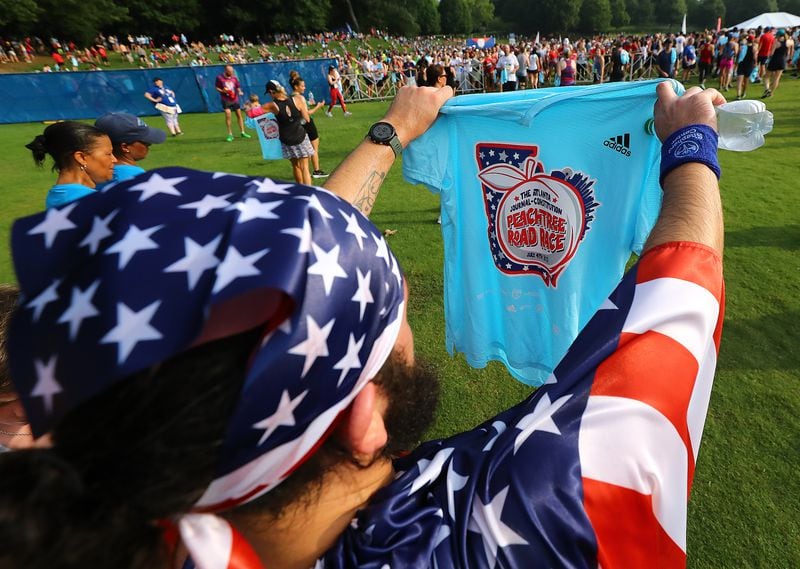 File photo of patriotically dressed runner Steve Boothe, Kennesaw, checks out his hard earned t-shirt after finishing the AJC Peachtree Road Race in Piedmont Park on Monday, July 4, 2022, in Atlanta.  “Curtis Compton / Curtis.Compton@ajc.com”