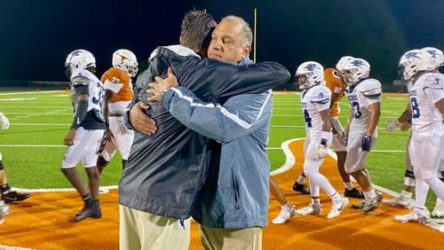 Norcross High coach Keith Maloof hugs his son Tyler Maloof, the coach at Lanier High, after the Blue Devils' 31-10 win at Lanier August 16, 2024. It was the first father-son coaching matchup in GHSA football since 2006. (AJC photo by Ken Sugiura)