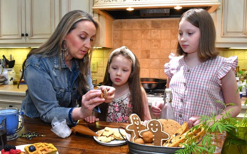 Cristina Kisner leads an impromptu lesson in making Alfajores (cookies filled with coconut dulce de leche) for daughters Hebe Gracey (center) and Josefina Gracey in their Roswell home. (Styling by Cristina Kisner / Chris Hunt for the AJC)