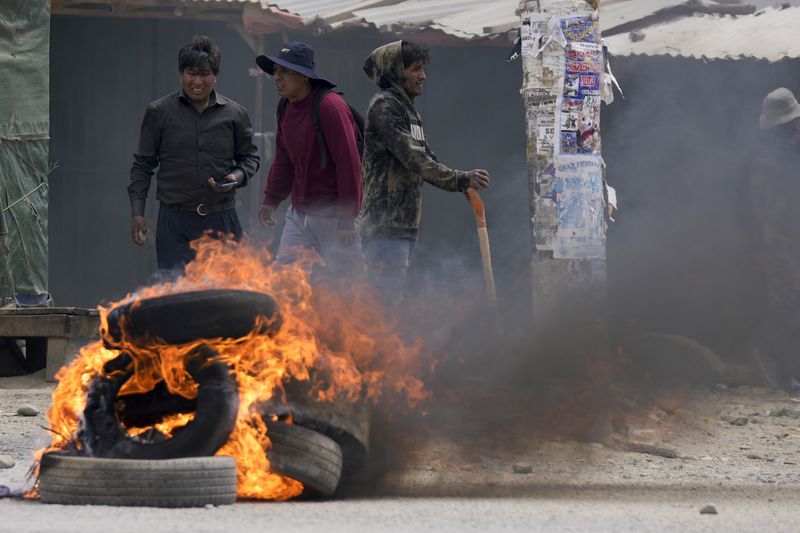 Tires burn as supporters of former President Evo Morales, marching to the capital to protest current President Luis Arce, face off with Arce supporters in El Alto, Bolivia, Sunday, Sept. 22, 2024. (AP Photo/Juan Karita)