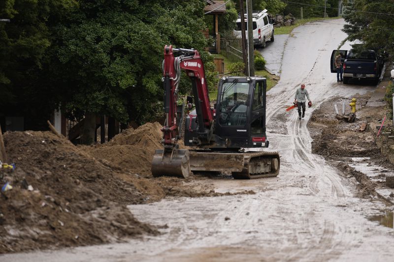 A person carries a chainsaw as cleanup begins in the aftermath of Hurricane Helene Tuesday, Oct. 1, 2024, in Hot Springs, N.C. (AP Photo/Jeff Roberson)