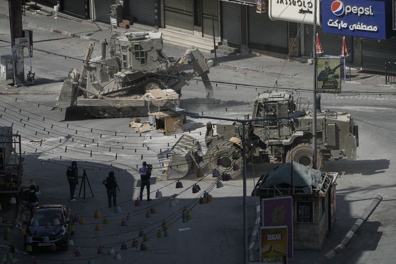 Israeli bulldozers move on a street during a military operation in the West Bank city of Jenin, Saturday, Aug. 31, 2024. (AP Photo/Majdi Mohammed)