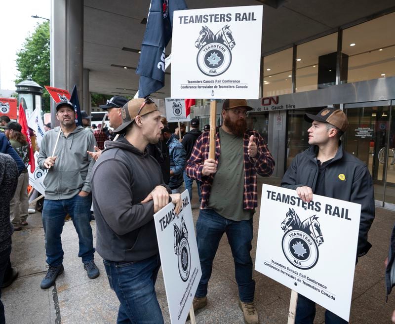 Rail workers picket in front of Canadian National headquarters on the first day of a nationwide rail shutdown, after workers were locked out by CN and CPKC when new contract agreements weren't reached by the midnight deadline, in Montreal, Thursday, Aug. 22, 2024. (Ryan Remiorz /The Canadian Press via AP)