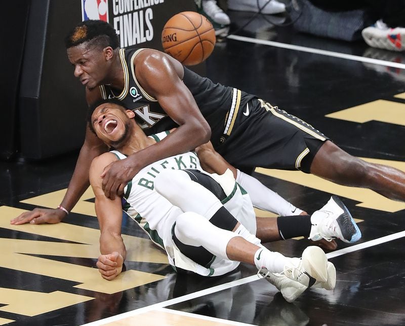 Hawks center Clint Capela and Milwaukee Bucks forward Giannis Antetokounmpo fall to the hardwood after battling at the basket during the third quarter of Game 4 of the Eastern Conference finals Tuesday, June 29, 2021, at State Farm Arena in Atlanta. Antetokounmpo left the game with an apparent knee injury. (Curtis Compton / Curtis.Compton@ajc.com)