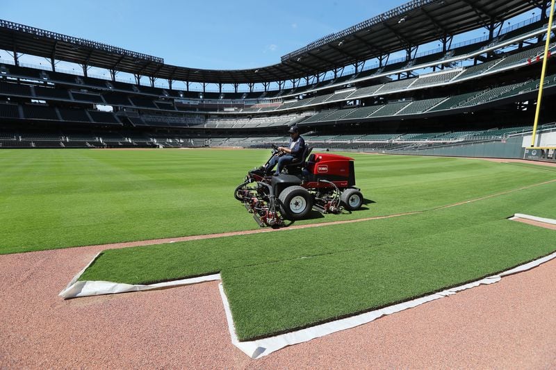 Field manager Anthony DeFeo, mowing left field at Truist Park on Wednesday, passes by extra sod used for any needed repairs.  