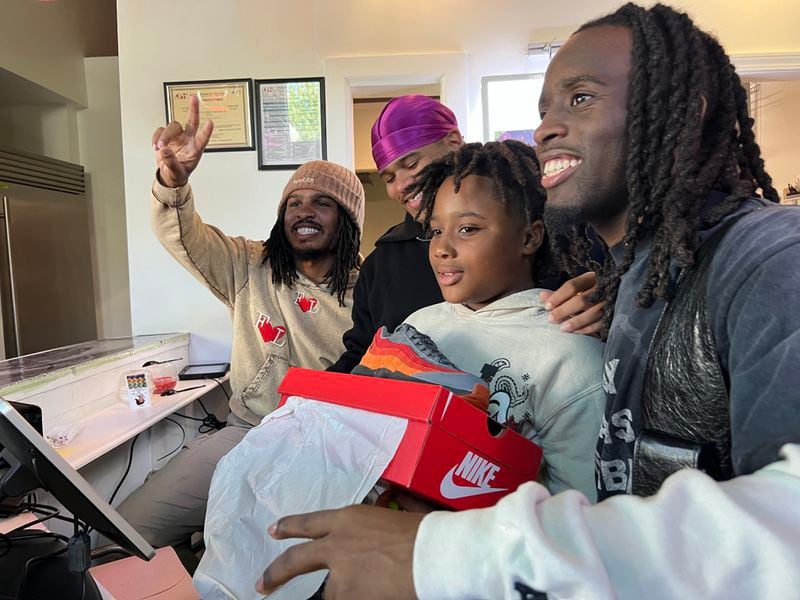 TikTok food critic Keith Lee, along with influencers Fanom and Kai Cenat, pose for a photo with a fan after giving out free Nike Air Max 95 "404 Day" sneakers during Lee's "community giveback" event in Atlanta on April 3, 2024.